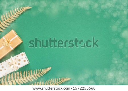 Festive green background with gold decoration , background with glitter shiny golden fern leaves and gift boxes , flat lay, top view, copy space