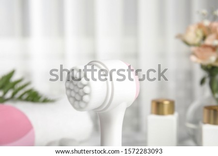 Modern face cleansing brush on blurred background. Cosmetic accessory