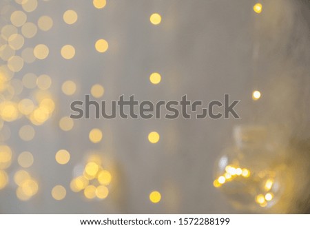 Blurred view of Christmas fairy lights on grey wall. Interior decoration