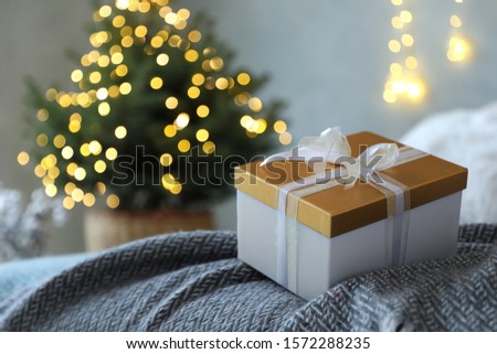 Christmas gift box on bed in festive interior
