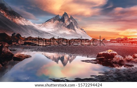 Impressive colorful sunset of Iceland. Dramatic view on magic rocky mount and perfect reflection. with clouds during sunrise. Amazing nature landscape near Stokksnes cape and Vestrahorn Mountain. 