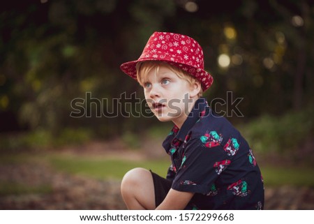 Young happy boy dressed up in Christmas outfit in lush park outdoors