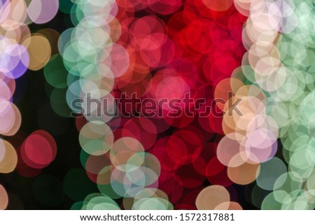 Red, green and pink Christmas light shiny abstract round bokeh on black background. Colourful Glitter bokeh from blurry decoration bulbs.