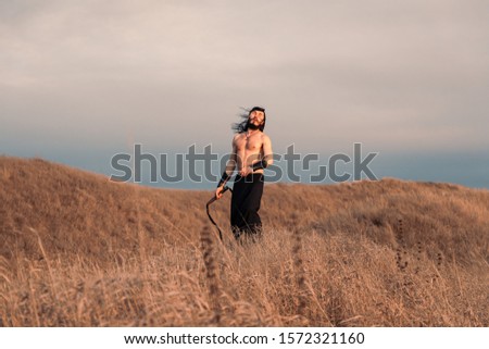 Young ukrainian man with long hair at the open steppe in Ukraine historical costume