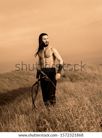 Young ukrainian man with long hair at the open steppe in Ukraine historical costume