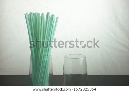 Conceptual of world issue on single use plastic against reusable steel straw. Straws in glass standing upright over dark surface. Focus at straws at center. Others in gradient blur.