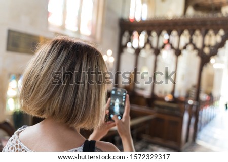 Stock photo of a young girl taking pictures with her cell phone in a church. Travel concept