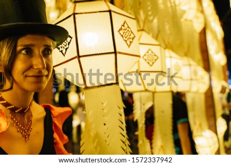Stock photo of a tightrope walker girl dressed in a black hat surrounded by a string of Chinese lanterns at night