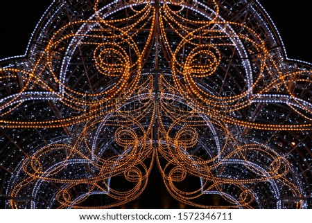 The interlacing of LED paths of orange and blue color creates a festive picture on a black background of the night sky.