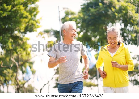 happy asian senior couple running exercising outdoors in park Royalty-Free Stock Photo #1572362428