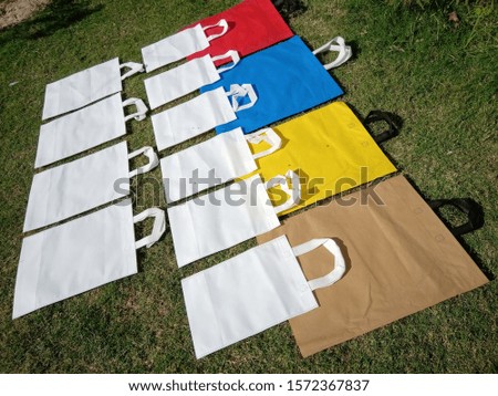amazing style of lying Non Woven Polypropylene Bags on green grass background, Eco Friendly Bags, Reusable bag, Shopping & Gift Bags, Environment Friendly Concept. Reduce, Reuse, Recycle