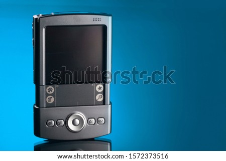 Old style PDA smartphone on isolated blue background. Royalty-Free Stock Photo #1572373516