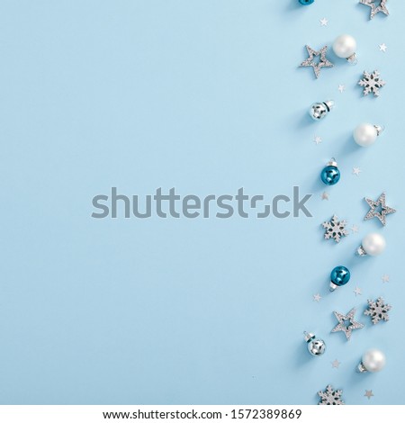 Christmas minimal mockup - white, glass and blue balls, snowflakes and stars confetti on blue background. Square composition, flat lay, top view. Empty copy space with xmas decoration border