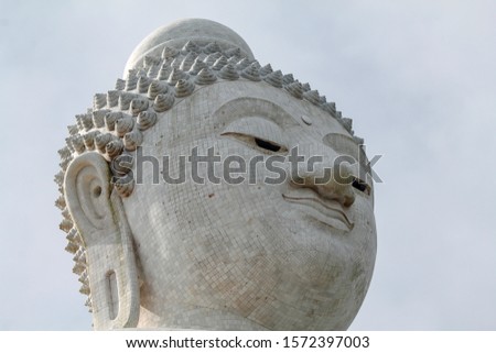 Close-up marble statue of a snow-white Big Buddha on the island of Phuket in Thailand. A giant Buddha figure made of marble bricks on Mount Nakaked in honor of the King of Thailand.