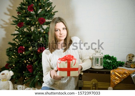 girl sits near a Christmas fir tree and holds in her hands a gift, Christmas nd vintage atmosphere, space for text