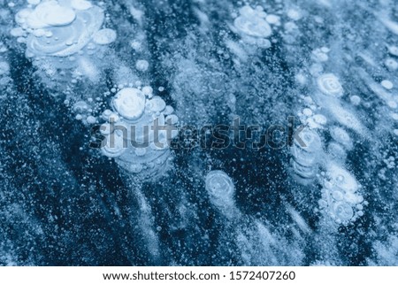 
ice texture with frozen air bubbles. winter dark background