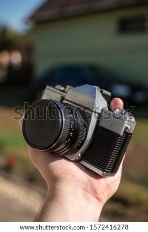 Old style analog camera with lens in hand