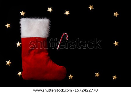 Red christmas sock with peppermint candies on black background and a copy space