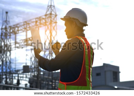 Engineer holding smartphone against building Electrical