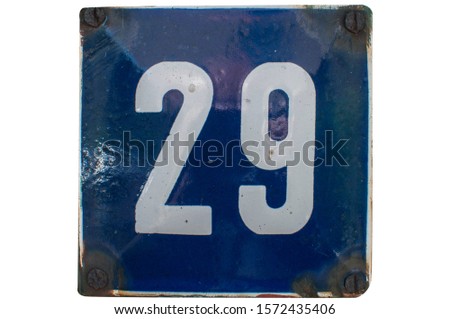 Weathered grunge square metal enameled plate of number of street address with number 29 closeup isolated on white background