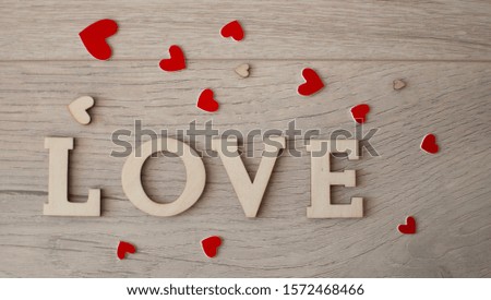 The word Love with red heart against a wooden background closeup