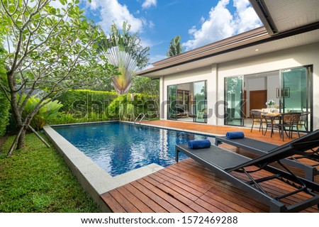 swimming pool and decking in garden of luxury home Royalty-Free Stock Photo #1572469288