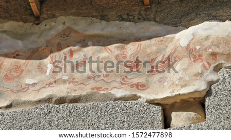 Remnants of painted frescoes-exterior wall of the cliff housing the Mogao caves rock cut into the local sandstone depicting Buddhist imagery spanning the 4th to the 14th century. Dunhuang-Gansu-China.