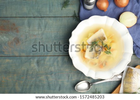 Delicious fish soup served on blue wooden table, flat lay. Space for text