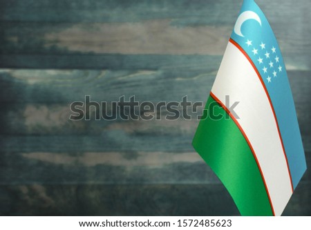 Fragment of the flag of Uzbekistan in the foreground blurred light background copy space