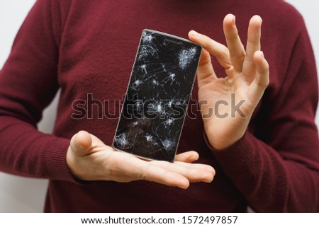 Man holding a cell phone after an accident. Digital phone with broke screen. Damaged display.