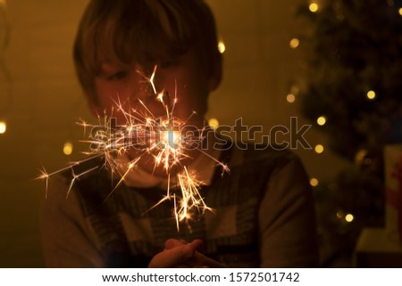 A child holds a sparkler, close-up. Sparkler and sparks macro photo festive background bokeh, magic atmosphere for Christmas and New Year