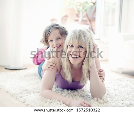 Young girl lying with mother on rug