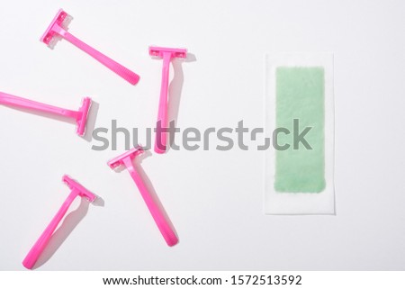 top view of female pink razors and depilation stripe on white background
