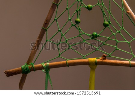 Dream catcher spiritual triangle shape object details wooden sticks threads netting and green yellow tape