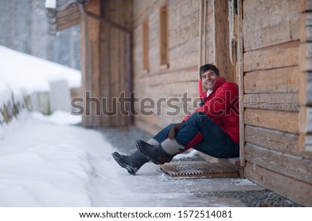 Man sitting outside log cabin