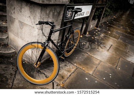 A stylish single speed black bike with golden rims parked in the corner of a street in London, England, United Kingdom