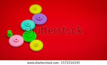 Many colored plastic gears on a red background