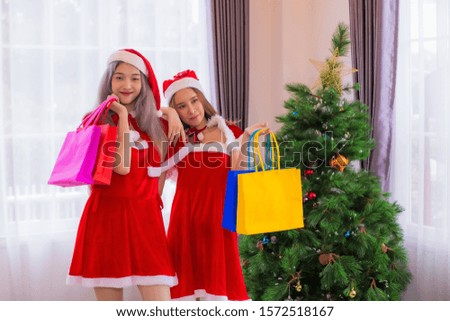 Beautiful two asian woman wearing hat and red Santa Claus  holding shopping bags 