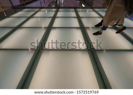 Photography of human feet. People walking on a glass white bridge in a shopping center. Concepts of shopping and lifestyles.