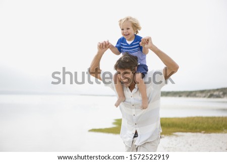 Father carrying boy on shoulders at beach