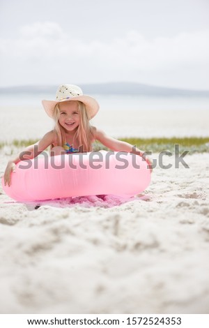 Portrait of young girl smiling with pink inflatable on beach