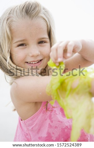 Young girl smiling and playing with seaweed