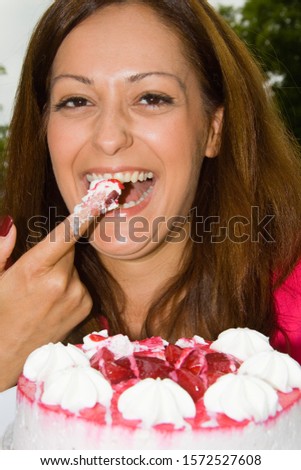 Young woman eating cake outdoors, smiling