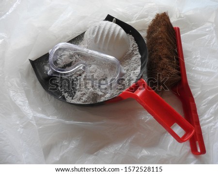 White asbestos on dustpan and brush. Plastic bag on background. Mask, filter, and goggles.  Asbestos removal, hazard, part of a serie.