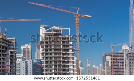 Aerial view of a skyscrapers under construction with huge cranes timelapse in Dubai. Business bay district with downtown on a background. United Arab Emirates