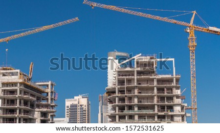 Aerial view of a skyscrapers under construction with huge cranes timelapse in Dubai. Business bay district with blue sky on a background. United Arab Emirates