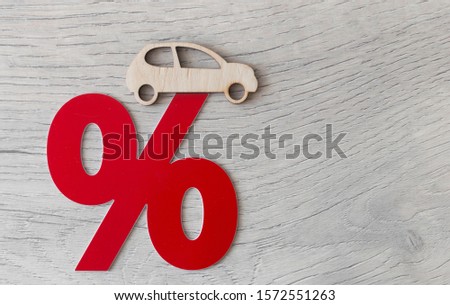 Wooden passenger car model and percent sign on a wood background. The concept of change of car prices .