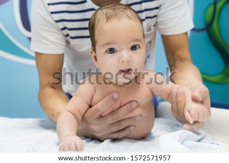 A small baby is lying on the table and he gets a massage. gymnastics for the child. healthy lifestyle.