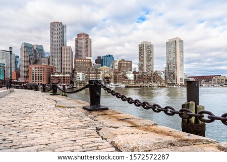 View of Boston skyline from a cobbled harbourwalk on a cloudy autumn morning