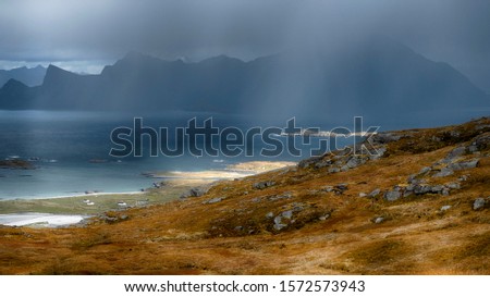 rainy autumn evening  
with storm clouds and the rays of the sun on the way up the mountain Ryten of Norway on Lofoten Islands 
